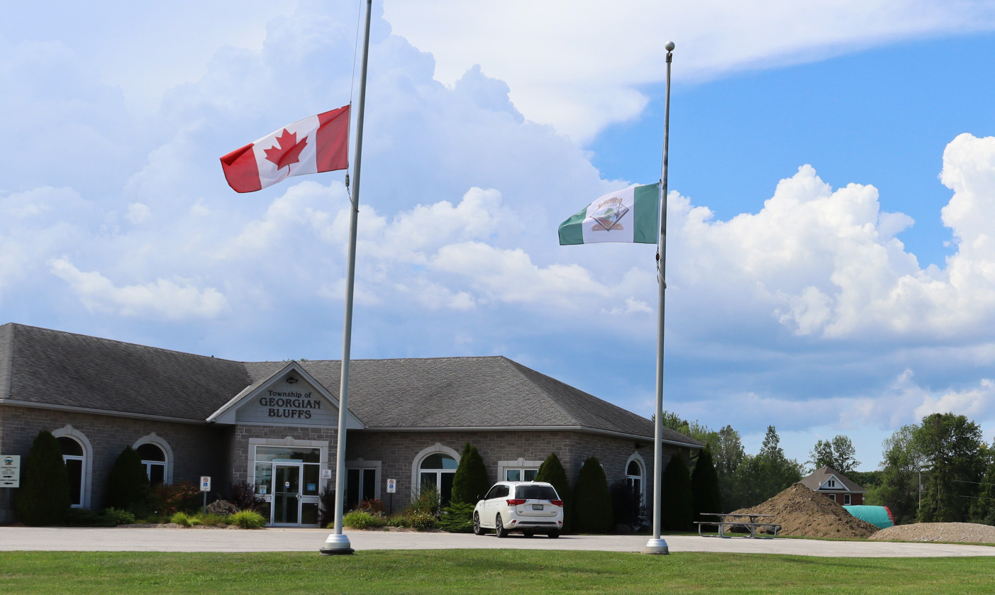The Canadian Flag and Township Flag at half mast in front of the office.