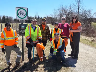 Staff from Goegrian Bluffs posing with the rail train sign, with litter cleanup equipment.